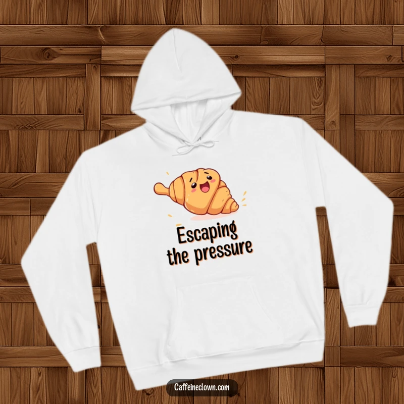 Funny croissant escape hoodie with a clumsy croissant character rolling away from a giant rolling pin, a warm and humorous apparel item.