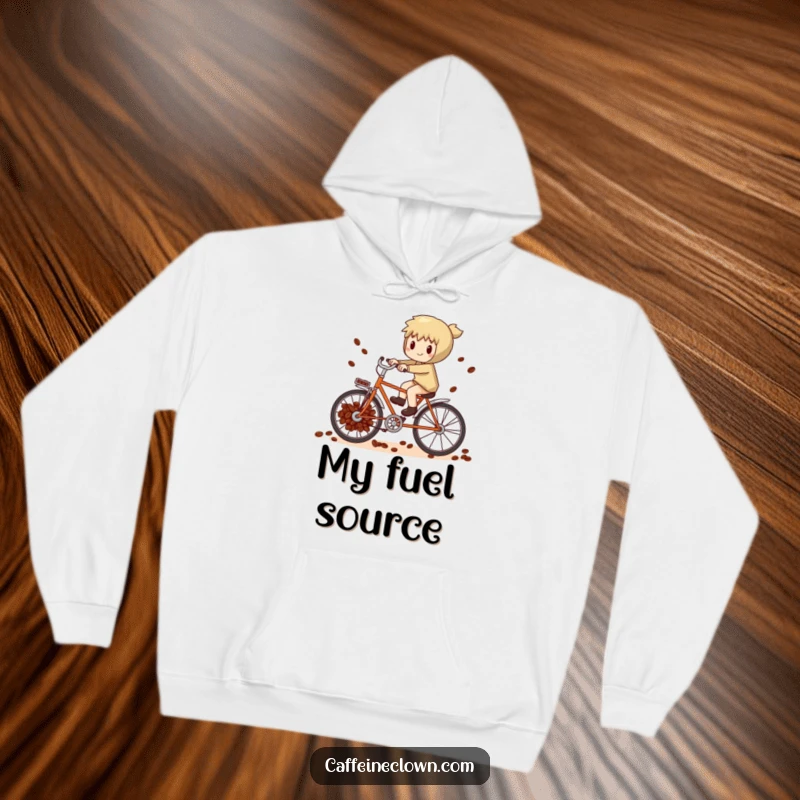 Funny whimsical character attempting to pedal a bicycle powered by coffee beans, featured on a warm hoodie.